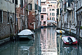 Boote, die entlang von Gebäuden in einem ruhigen Kanal festgemacht sind; Venedig, Italien