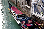 Gondel an einem Gebäude in einem Kanal festgemacht; Venedig, Italien