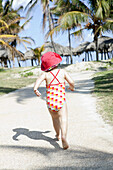 Kind, das barfuß einen Pfad hinunter in Richtung Strand läuft; Varadero, Kuba
