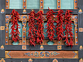 Rote Paprikaschoten hängen an einer verzierten Wand; Paro, Bhutan
