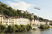 Bubble Gondola, die über alte Gebäude entlang eines Flusses fährt; Grenoble, Frankreich