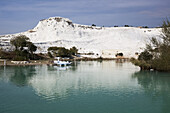 Türkisfarbenes Wasser in einem Becken, in dem sich eine weiße Wand aus Mineralienablagerungen spiegelt; Pamukkale, Türkei