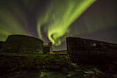 Nordlichter über der Stadt Djupavik entlang der Strandir-Küste, hier tanzen sie über der alten Heringsfabrik und dem Schiffswrack; Djupavik, Island