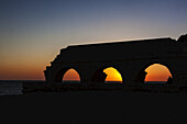 Silhouette eines römischen Aquädukts mit Bögen bei Sonnenuntergang im Caesarea Maritima-Nationalpark; Israel