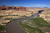 Low Altitude Aerial View Of The Colorado River Winding Through Canyon Country Of Southern Utah, A Bridge Spanning The River In The Background With Red Rock Canyon Walls And Blue Skies; Utah, United States Of America