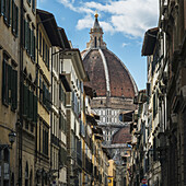 Blick auf das Kuppeldach einer Kirche, vorbei an Reihen von Wohn- und Geschäftsgebäuden; Florenz, Toskana, Italien
