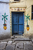 Eine mit lokalen Hindu-Motiven, einschließlich Hindu-Hakenkreuzen, bemalte Tür zu einem Haus; Varanasi, Indien