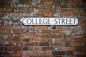 Schild für College Street an einer Backsteinmauer; Winchester, Hampshire, England
