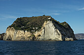 Hohe zerklüftete Klippen der Gemeinde Bacoli mit einem Leuchtturm auf der Landzunge; Neapel, Kampanien, Italien