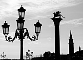 Silhouette eines verzierten Lampenpfostens und einer Statue auf einer Säule; Venedig, Italien
