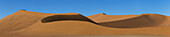 Das Licht des Sonnenaufgangs beleuchtet die großen, roten Sanddünen in Sossusvlei, einem Teil der Namib-Wüste; Namibia