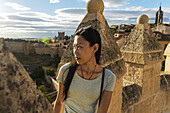 Asiatisches Mädchen, das auf den alten Mauern von Segovia sitzt; Segovia, Kastilien-León, Spanien