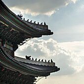 Detaillierte Dachlinie des Gyeongbokgung-Palastes vor einem blauen Himmel mit Wolken; Seoul, Südkorea