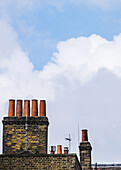 Schornsteine gegen einen blauen Himmel mit Wolken; London, England