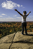 Frau auf einer Klippe stehend mit Blick auf die Herbstfarben des Algonquin Parks; Ontario, Kanada