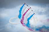 Red Arrows air display, nine planes flying in formation with colourful contrails; South Shields, Tyne and Wear, England
