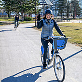 A woman cycling on a paved trail in an urban area; Vancouver, British Columbia, Canada