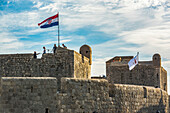 Tourists on the walls of a historic fortication with flag; Dubrovnik, Dubrovnik-Neretva County, Croatia