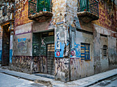 Weathered facade of residential building with advertising on the wall; Havana, Cuba