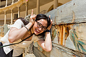 Young female tourist poses with bull image at bull fighting ring, Plaza de Toros de Ronda; Ronda, Malaga, Andalucia, Spain