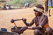 Hamer woman preparing a ceremonial drink at a bull jumping ceremony, which initiates a boy into manhood, in the village of Asile, Omo Valley; Southern Nations Nationalities and Peoples' Region, Ethiopia