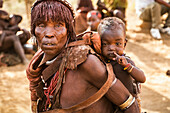 Eine Hamer-Frau trägt ein Baby bei einer Stiersprung-Zeremonie, mit der ein Junge in die Männlichkeit eingeführt wird, im Dorf Asile, Omo-Tal; Region der Nationalitäten und Völker des Südens, Äthiopien