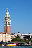 Campanile bell tower and domes of St Mark's basilica in St Mark's Square across Grand Canal with vaporetto, San Marco; Venice, Veneto, Italy