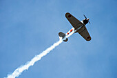 The Mitsubishi A6M "Tora" Zero, owned by the Olympic Flight Museum, trailing smoke while performing aerobatic manoeuvres in the 2019 Olympic Air Show, Olympic Airport; Olympia, Washington, United States of America