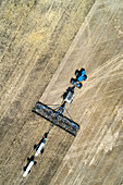 Aerial view of air seeder in field with white ammonia tanks, near Beiseker; Alberta, Canada