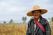 Ein Bauer steht auf einem Feld und trägt einen Strohhut; Taungyii, Shan-Staat, Myanmar