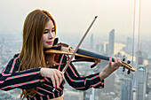 Female performer plays violin at a venue overlooking Bangkok; Bangkok, Thailand