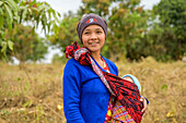 Young mother standing with her baby in a sling; Taungyii, Shan State, Myanmar