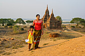 Portrait of a mother and daughter while selling drawings, a Buddhist temple the background; Bagan, Mandalay Region, Myanmar