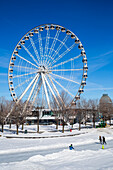 The Big Wheel at the old port in winter with ice skaters on the ice below; Montreal, Quebec, Canada