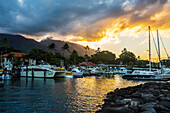 Yachts, sailboats and tour boats moored in the Lahaina harbour at sunset with volcanic island peaks in the distance; Lahaina, Maui, Hawaii, United States of America