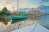 Bunte Uferpromenade von Belize City in der Abenddämmerung mit Spiegelungen im ruhigen Wasser; Belize City, Belize District, Belize