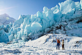 Wanderer am Rande des zugefrorenen Portage Lake und Blick auf das Eis des Portage Glacier, Süd-Zentral-Alaska und südlich von Anchorage; Alaska, Vereinigte Staaten von Amerika