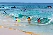 Surfers and body boarders play in the surf waves on Makena beach in on Maui, Hawaii, a popular tourist beach near Kihei on the pacific ocean and a destination for family travellers; Kihei, Maui, Hawaii, United States of America