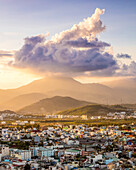 Glühender Sonnenuntergang über den Bergen und dem Stadtbild von Nha Trang; mit einer großen Wolkenformation über den Bergen; Nha Trang, Provinz Khanh Hoa, Vietnam