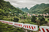 Barrieren in der Landschaft mit einer Stadt und üppigem Blattwerk, das die Karstkalksteinformationen bedeckt; Insel Cat Ba, Vietnam
