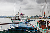 Tour boat and fishing boat at a waterfront dock in Ha Long Bay; Quang Ninh Province, Vietnam