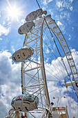 View from directly below the cables and pods of the London Eye with a blue sky and clouds in the background; London, England