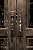 Long door handles and locks on a set of double wooden doors with carved decorative designs; Franklin, Tennessee, United States of America