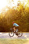 Radfahrer auf einer Straße mit hellem Sonnenlicht, das durch die Bäume dringt, in der Nähe der Trace Nachez Bridge; Franklin, Tennessee, Vereinigte Staaten von Amerika