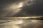 Silhouetted lighthouses along the coastline under dramatic cloudy sky; Whitburn Village, Tyne and Wear, England