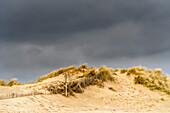 Sand und Strandgräser unter dunklem Himmel; South Shields, Tyne and Wear, England