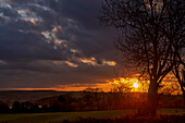 Goldener Sonnenuntergang am Himmel mit dunklen Wolken über der Landschaft; Ravensworth, North Yorkshire, England