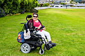 Maori woman with Cerebral Palsy in a wheelchair on a grass field in a park area; Wellington, New Zealand