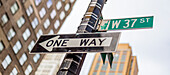 Straßenschilder an einem Pfosten, eine Einbahnstraße und West 37th Street, Manhattan; New York City, New York, Vereinigte Staaten von Amerika
