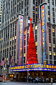 Radio City Music Hall decorated at Christmastime and tourists gathered at the corner of the intersection outside the entrance; New York City, New York, United States of America
